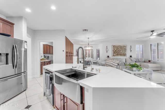 kitchen with sink, hanging light fixtures, light tile patterned floors, stainless steel refrigerator with ice dispenser, and a center island with sink