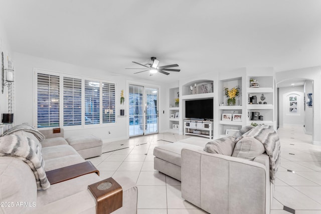 living room featuring built in shelves, ceiling fan, and light tile patterned floors