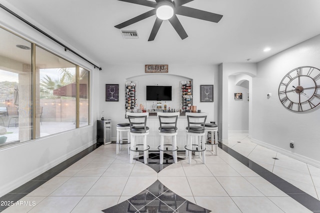 tiled dining room featuring ceiling fan and bar