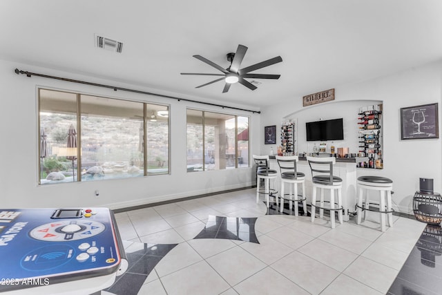 dining area with ceiling fan, indoor bar, and tile patterned floors