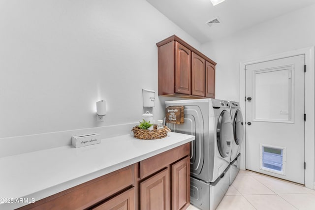 washroom featuring cabinets, washing machine and dryer, and light tile patterned floors