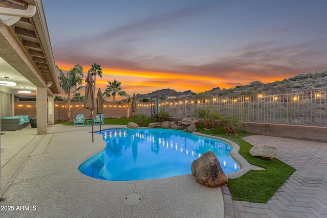 pool at dusk with a patio area