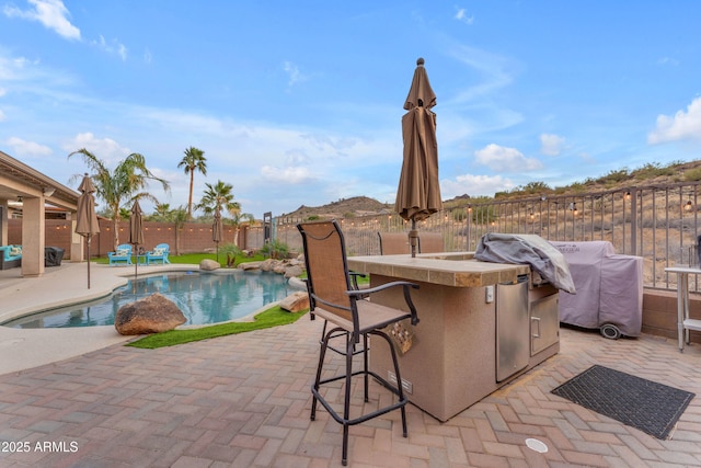 view of swimming pool featuring a grill, exterior bar, and a patio