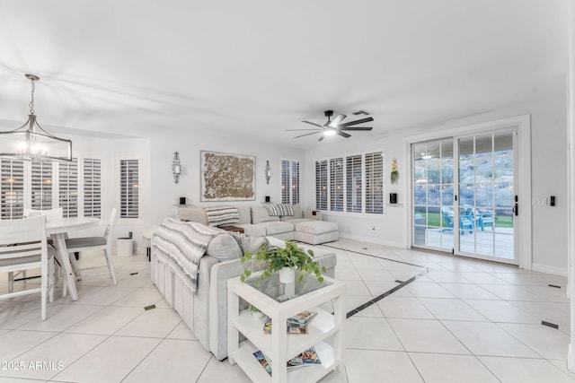 tiled living room with ceiling fan with notable chandelier