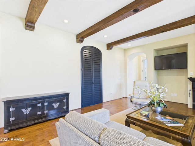 living room featuring arched walkways, beamed ceiling, recessed lighting, and wood finished floors
