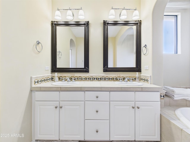 full bathroom with double vanity and a relaxing tiled tub