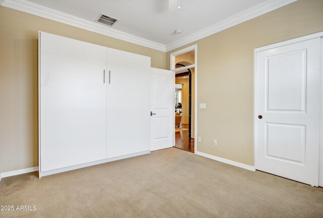 unfurnished bedroom featuring carpet flooring, crown molding, baseboards, and a closet