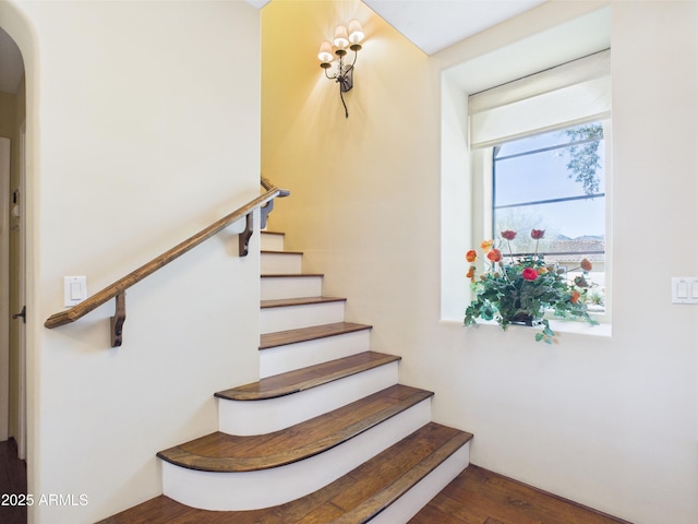 stairway with wood finished floors and arched walkways