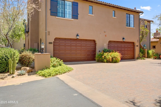 view of front of home with an attached garage, stucco siding, and decorative driveway