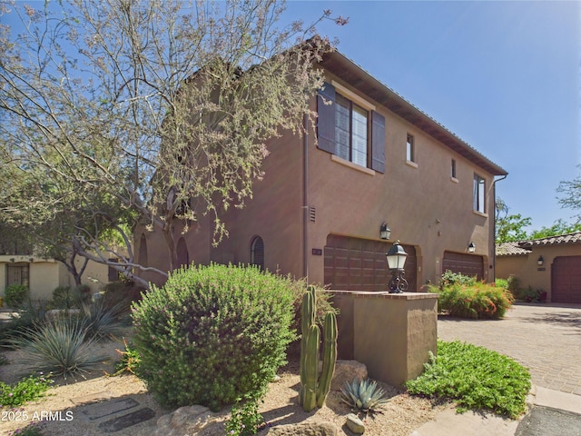 view of side of property with a garage, stucco siding, and driveway