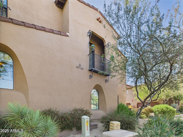 view of side of home with a balcony and stucco siding