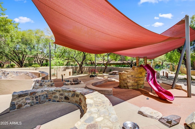 view of patio featuring a playground and fence