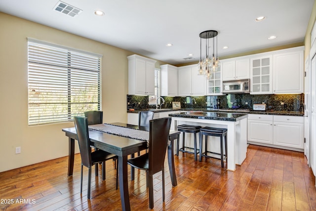 kitchen featuring stainless steel microwave, dark countertops, white cabinets, a chandelier, and dark wood-type flooring