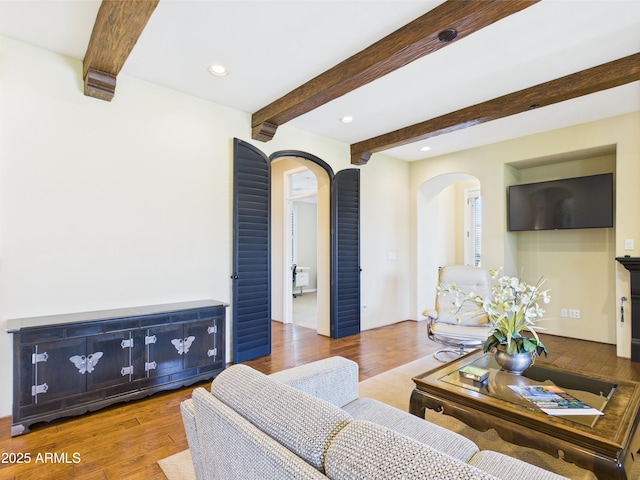 living room featuring arched walkways, beam ceiling, recessed lighting, and wood finished floors