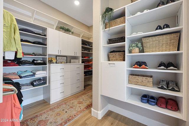 walk in closet with built in desk and light wood-type flooring