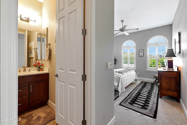 carpeted bedroom with sink, ensuite bath, and ceiling fan