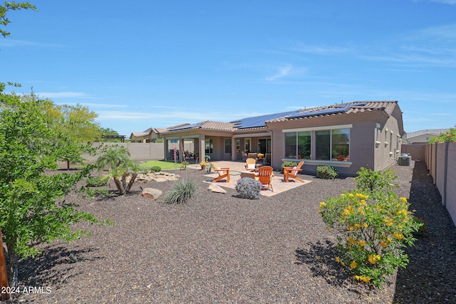 back of property featuring an outdoor fire pit, central AC, solar panels, and a patio