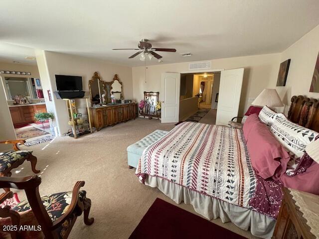 carpeted bedroom featuring ceiling fan and ensuite bathroom