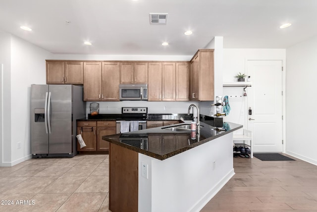 kitchen featuring light hardwood / wood-style floors, dark stone countertops, sink, and appliances with stainless steel finishes