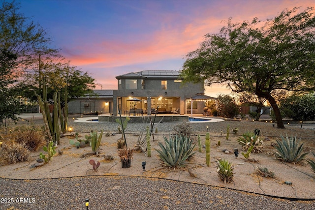 19428 E Hunt Hwy, Queen Creek, AZ 85142 - back of house at dusk with a gazebo, stucco siding, an outdoor pool, solar panels, and a patio