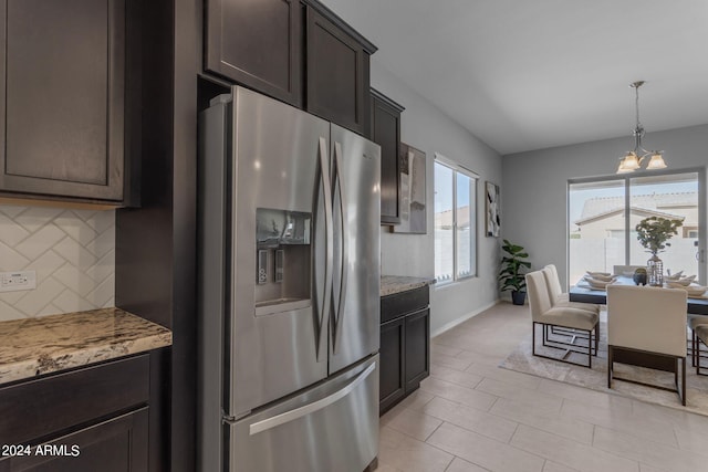 kitchen with dark brown cabinetry, tasteful backsplash, a notable chandelier, light stone counters, and stainless steel fridge with ice dispenser