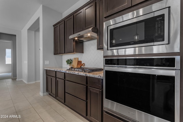 kitchen with light stone countertops, appliances with stainless steel finishes, decorative backsplash, dark brown cabinets, and light tile patterned flooring