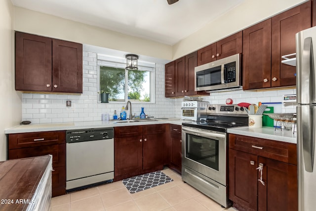 kitchen featuring decorative backsplash, light tile patterned floors, stainless steel appliances, and sink