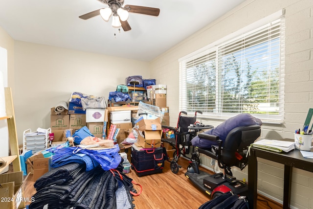 office space featuring hardwood / wood-style floors, ceiling fan, and brick wall