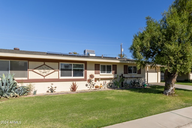 single story home featuring solar panels, cooling unit, a garage, and a front lawn