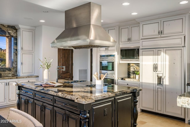 kitchen featuring built in appliances, island range hood, a center island, and light stone countertops