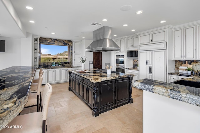 kitchen featuring exhaust hood, white cabinets, built in appliances, tasteful backsplash, and light stone counters