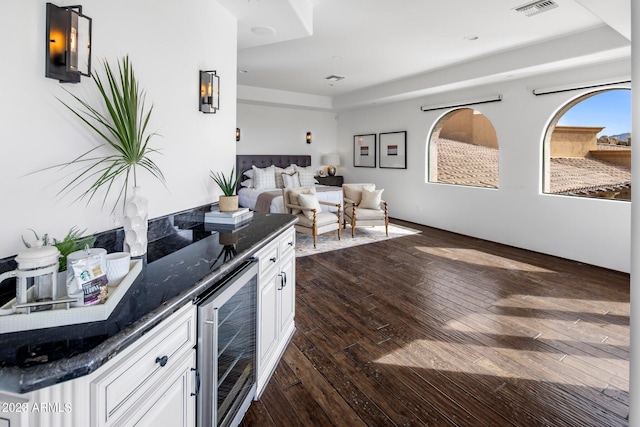 kitchen featuring white cabinets, dark hardwood / wood-style floors, wine cooler, and dark stone countertops