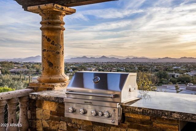 patio terrace at dusk featuring a mountain view, an outdoor kitchen, and area for grilling