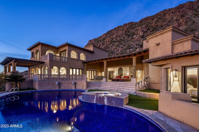 pool at dusk with a mountain view, an in ground hot tub, and a patio