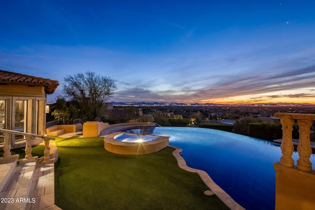 pool at dusk featuring an in ground hot tub