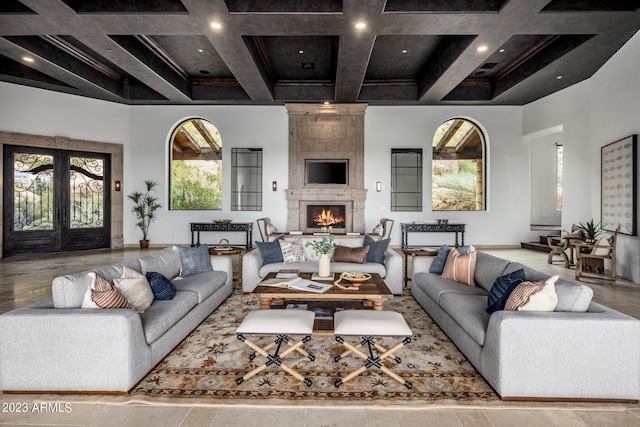 living room featuring beam ceiling, a fireplace, a healthy amount of sunlight, and coffered ceiling