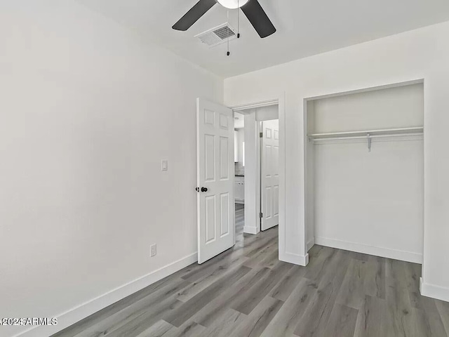 unfurnished bedroom with ceiling fan, light wood-type flooring, and a closet