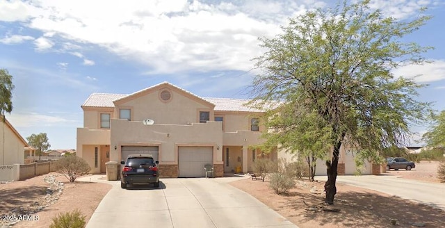 view of front of house with fence, a tiled roof, concrete driveway, stucco siding, and a garage