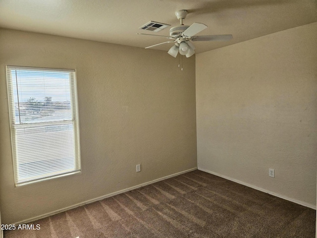 spare room featuring visible vents, ceiling fan, baseboards, and dark colored carpet