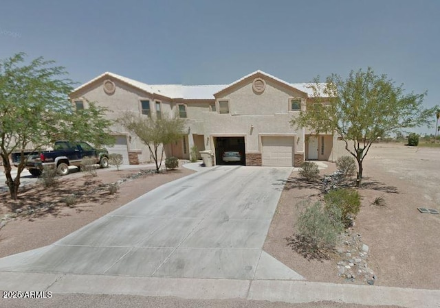 view of front of house with stucco siding, concrete driveway, and an attached garage