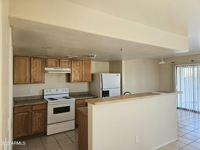 kitchen featuring white appliances, light tile patterned flooring, brown cabinets, and under cabinet range hood