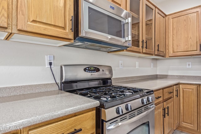 kitchen featuring glass insert cabinets, appliances with stainless steel finishes, and light countertops