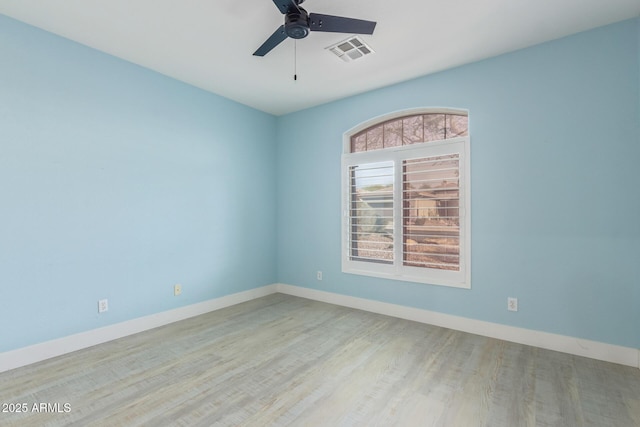 spare room with a ceiling fan, wood finished floors, visible vents, and baseboards