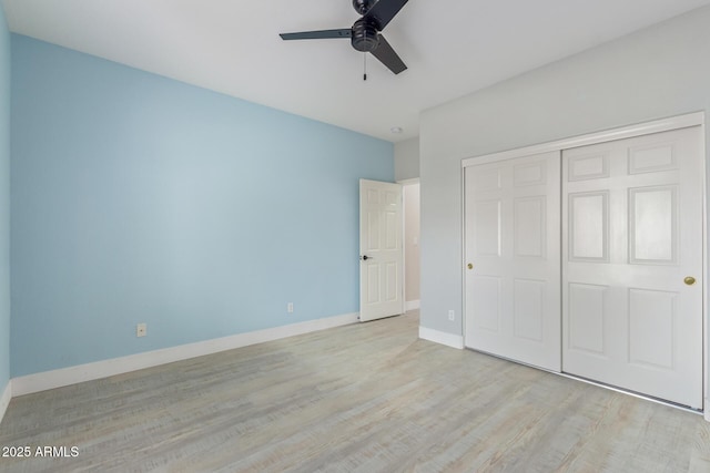 unfurnished bedroom featuring a ceiling fan, a closet, light wood-style flooring, and baseboards