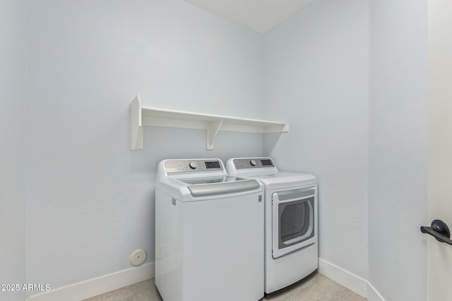 laundry room featuring laundry area, light wood-style flooring, baseboards, and washer and clothes dryer