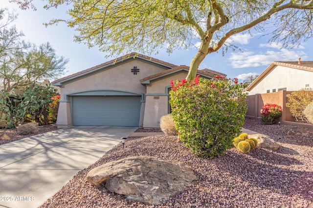 view of front facade with an attached garage, fence, driveway, a tiled roof, and stucco siding