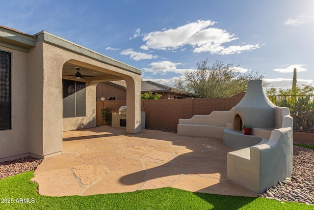 view of patio featuring exterior kitchen, a fenced backyard, and a ceiling fan