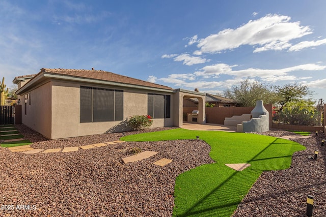 back of property with a fenced backyard, a tiled roof, a patio, and stucco siding