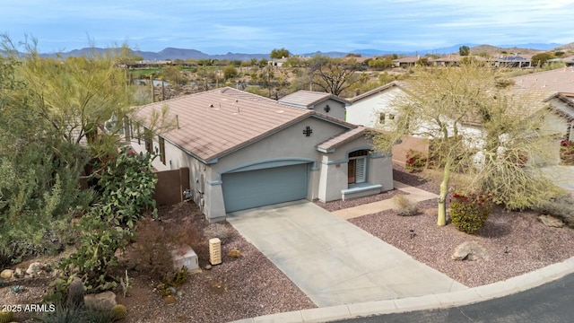 mediterranean / spanish home with stucco siding, an attached garage, a mountain view, driveway, and a tiled roof