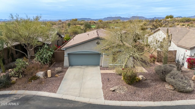 view of front of home featuring driveway, a garage, a tiled roof, a mountain view, and stucco siding